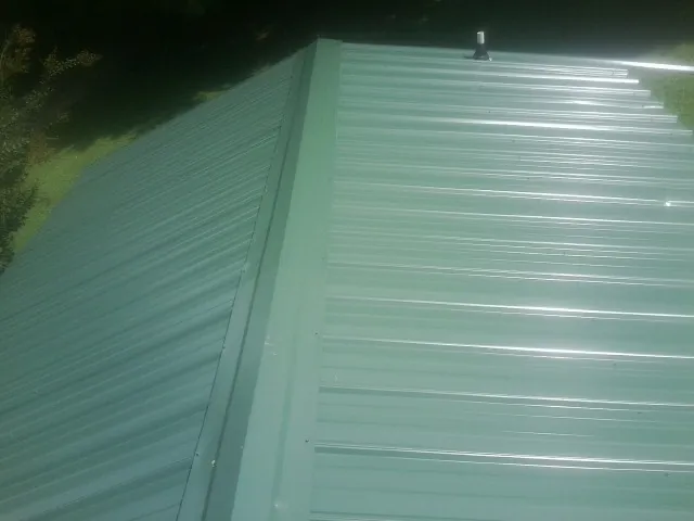 New green metal panels meeting at the ridge of a roof — Flat Roof Repair work by our crew in Saint Paul