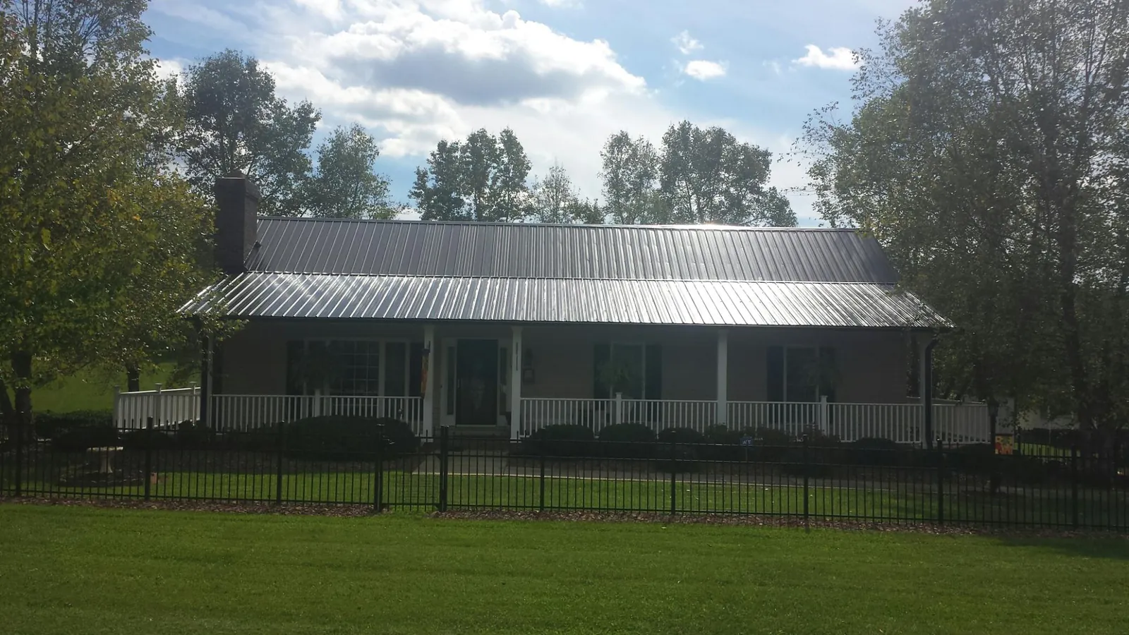 Gray metal roof on a brick ranch with a full width front porch — Gutter Guard Installation work by our crew in Saint Paul